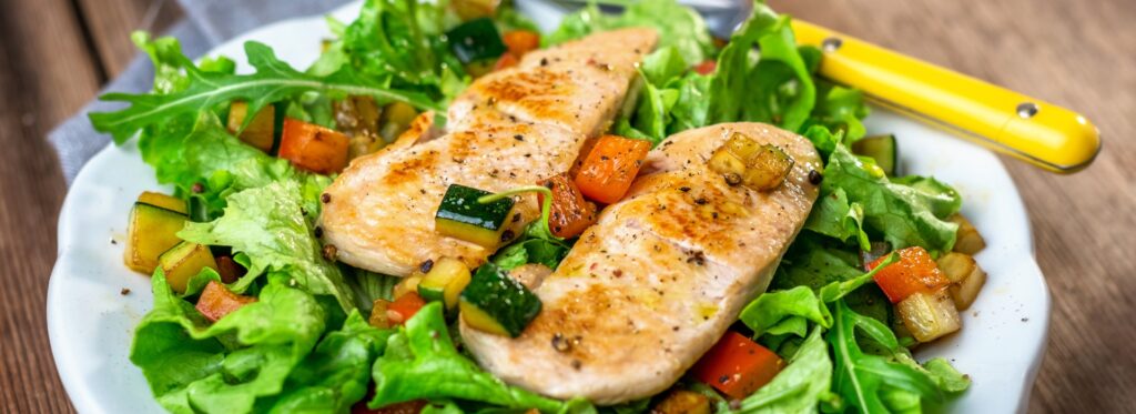 Grilled chicken breasts on a bed of salad