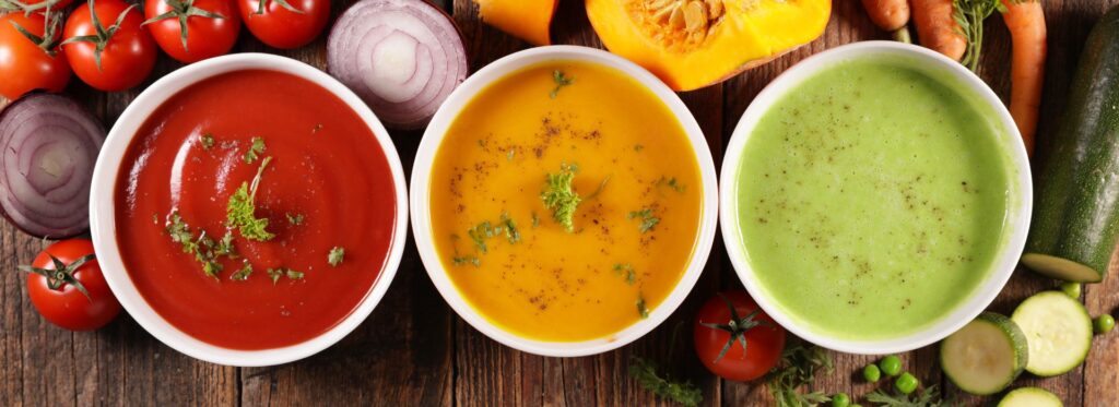 3 Different bowls of soup on a wooden table