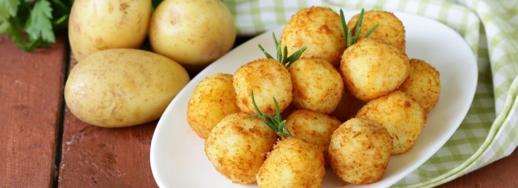 Raw and cooked potatoes on a wooden table